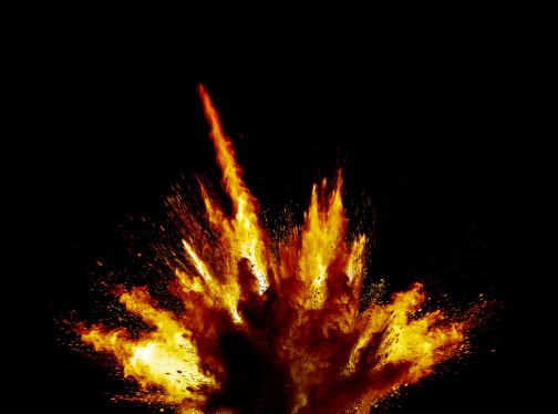 Impact and explosion with fire shock wave and dust particles on a black background.