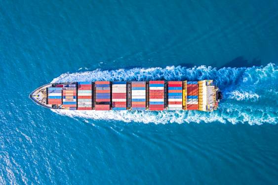 overhead shot as cargo ship sails on a blue sea.