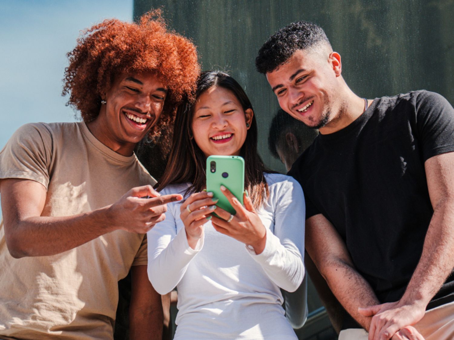 Three people smiling and all looking at a phone together
