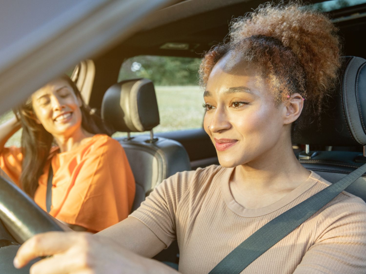Two women smiling and driving in a car