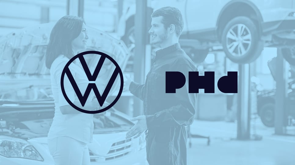Blue graphic of a man in an auto repair shop with VW and PHD logos placed over