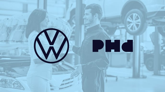 Blue graphic of a man in an auto repair shop with VW and PHD logos placed over
