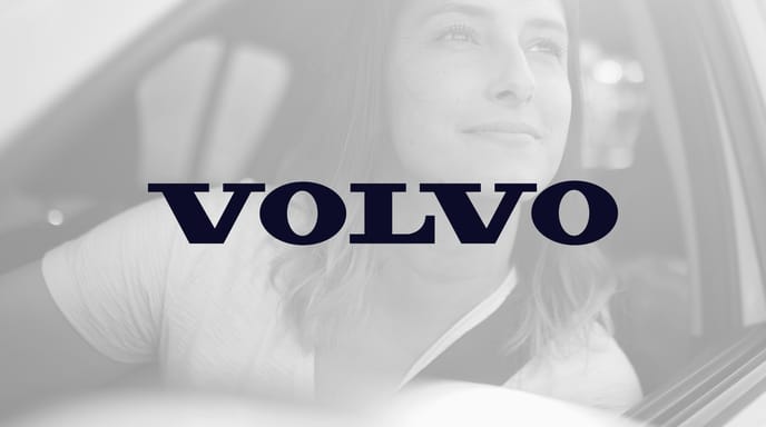 Woman smiling and looking out of the window of her Volvo SUV in black and white, with the Volvo logo in the center