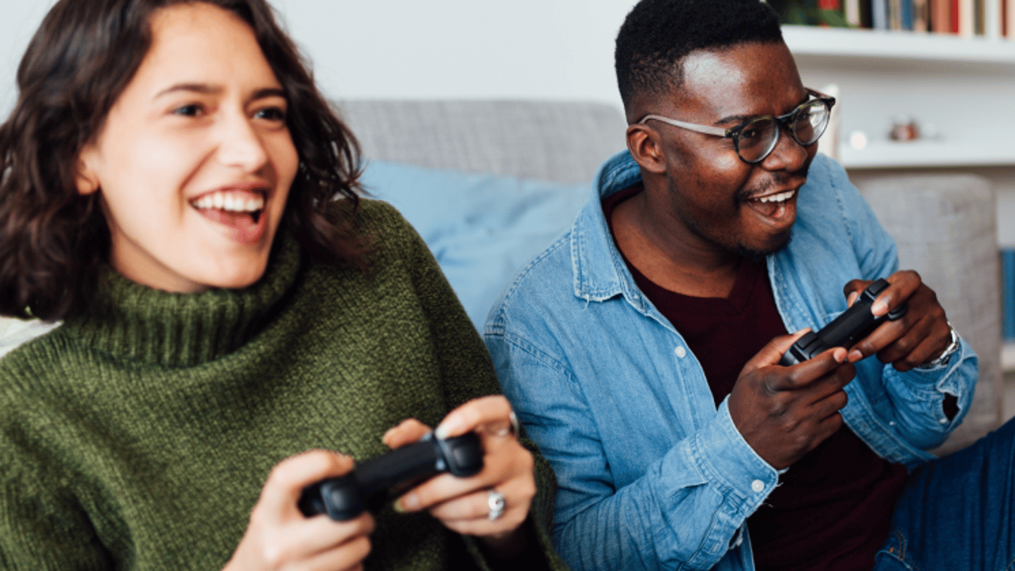Man and woman playing video games on a couch