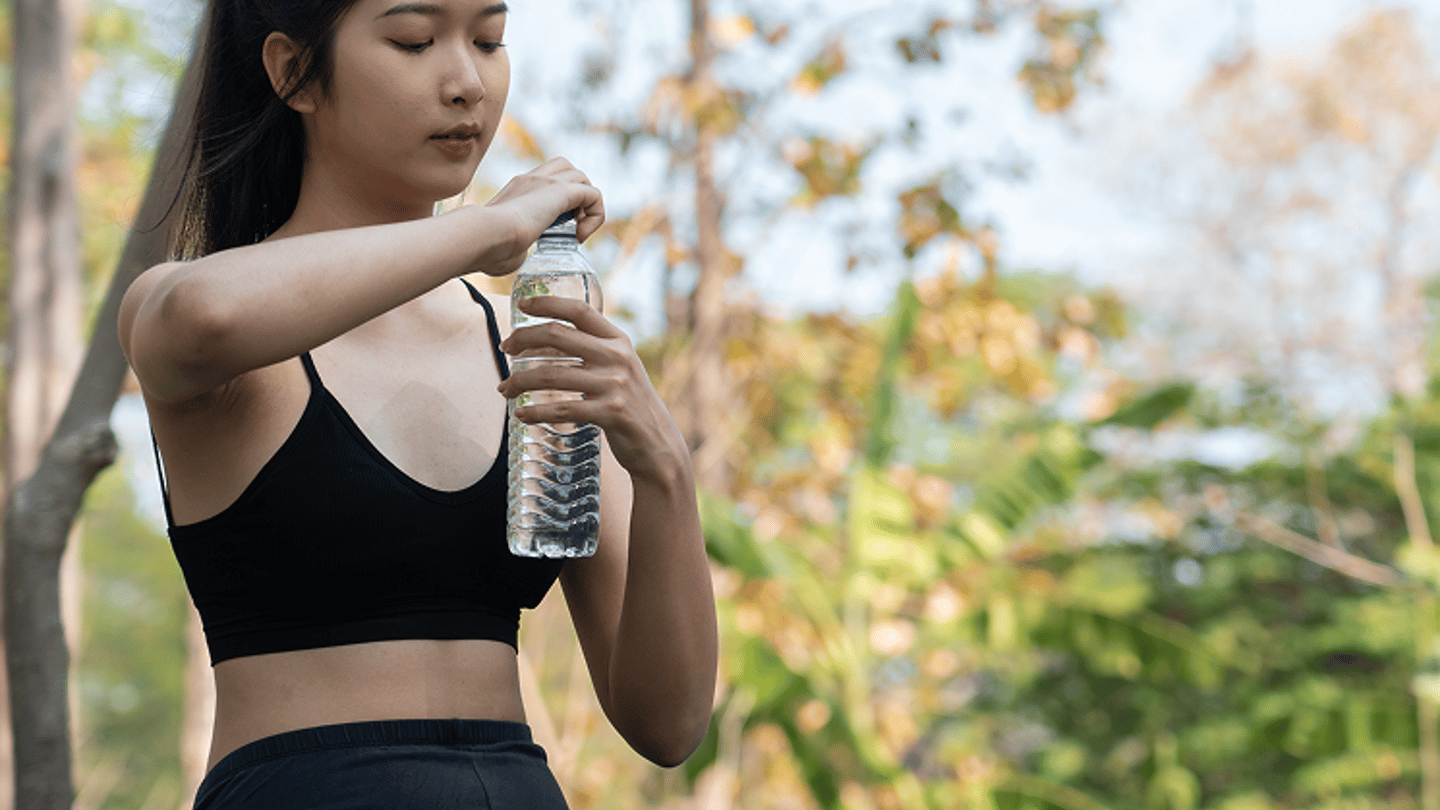 Woman sitting outside doing yoga taking a drink of water