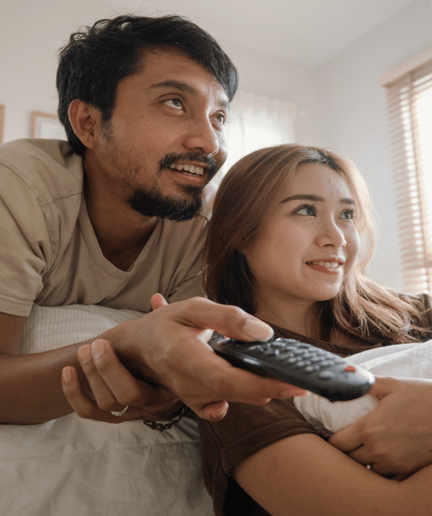 A couple using their remote and looking for something to watch on TV