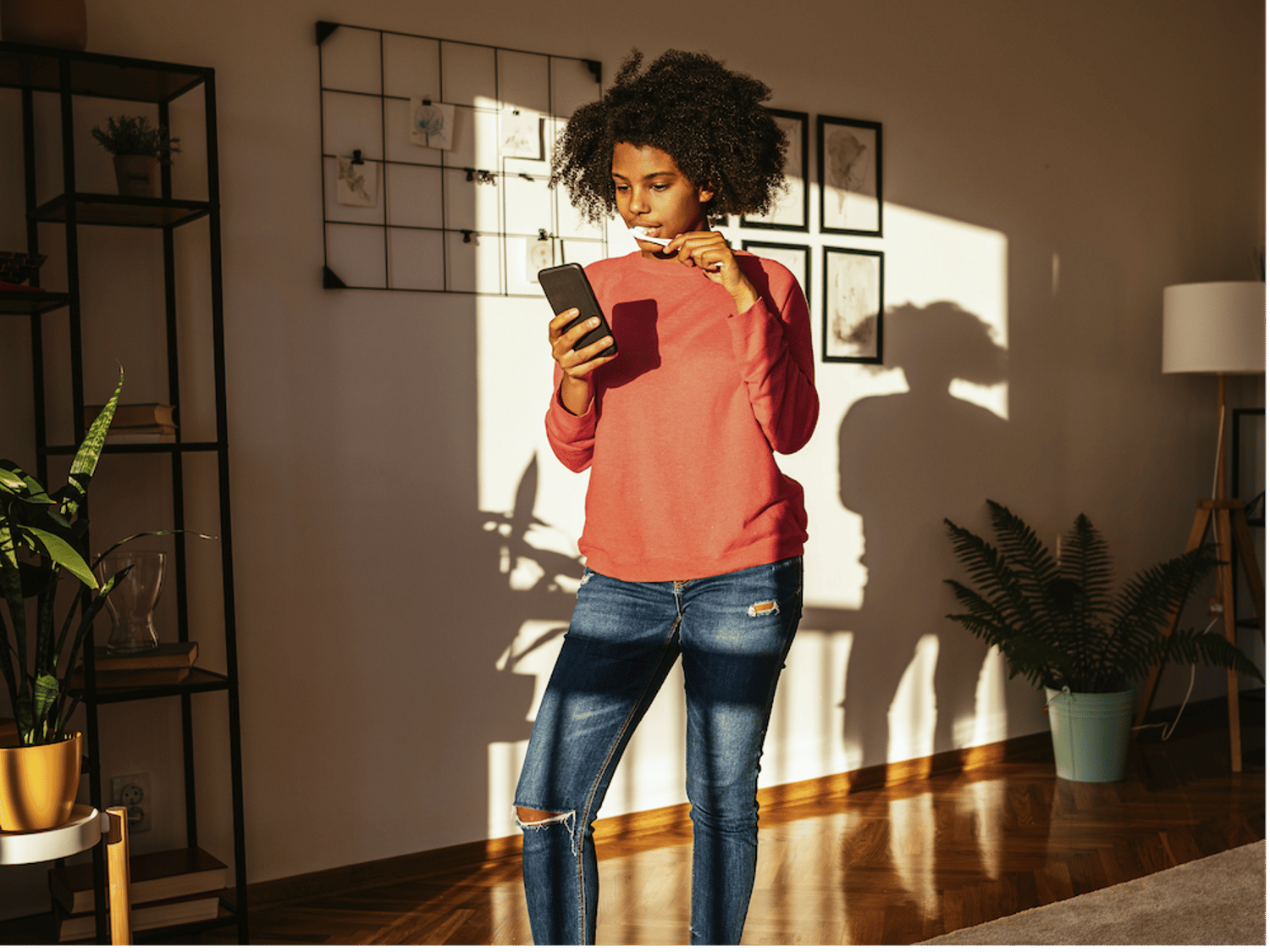 スマートフォンを操作しながら歯を磨くティーンエイジャーの画像