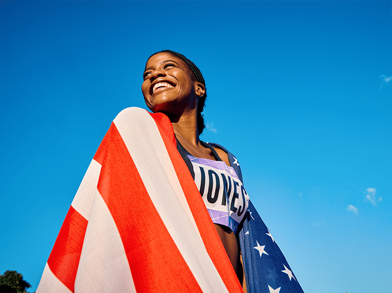 An olympian smiling and wrapped in the American flag