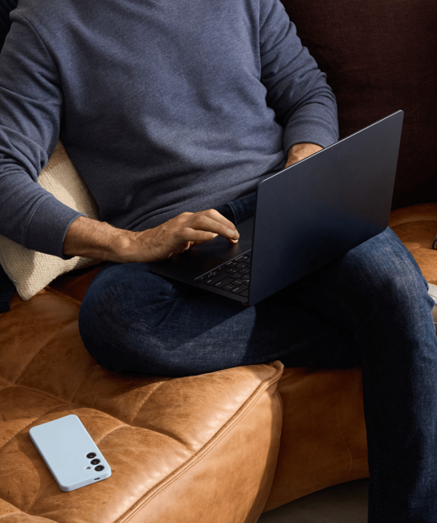 Person sitting on a sofa and working on their laptop